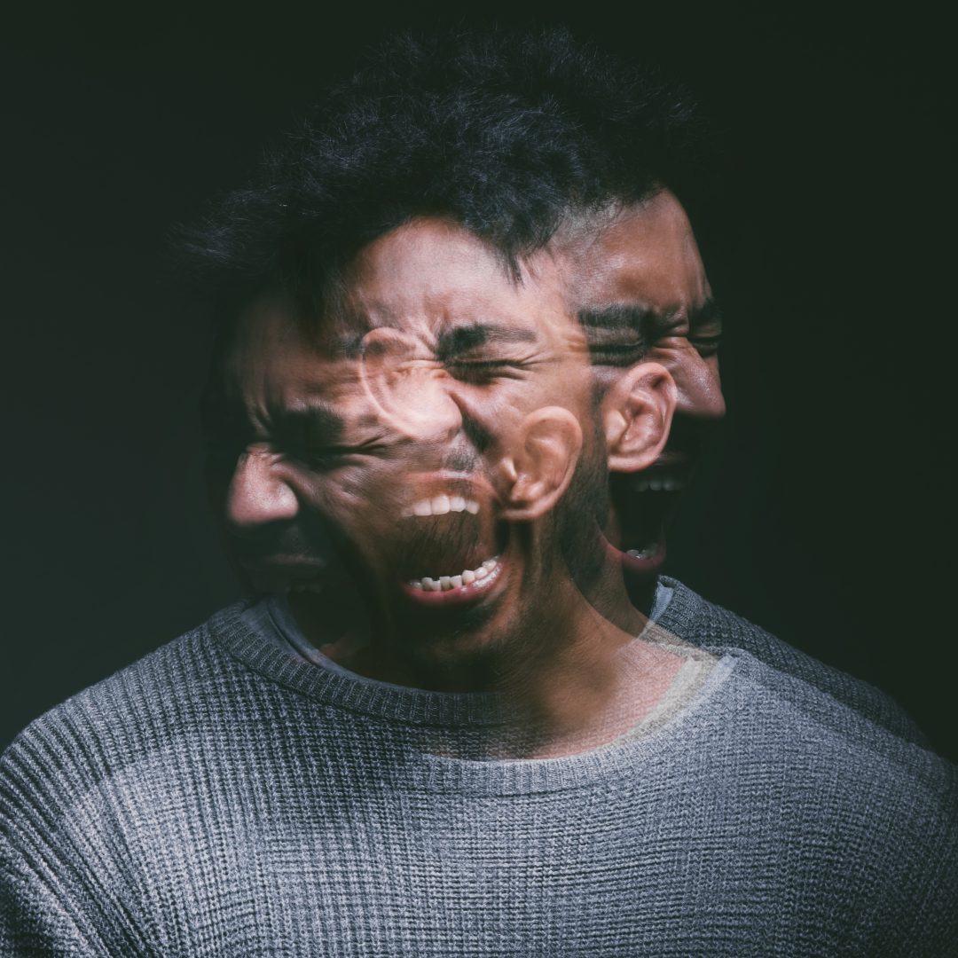 Studio shot of a young man experiencing mental anguish and screaming against a black background